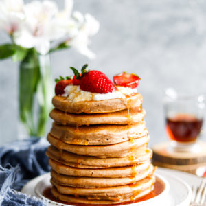 tall stack of fluffy pancakes with strawberries on top