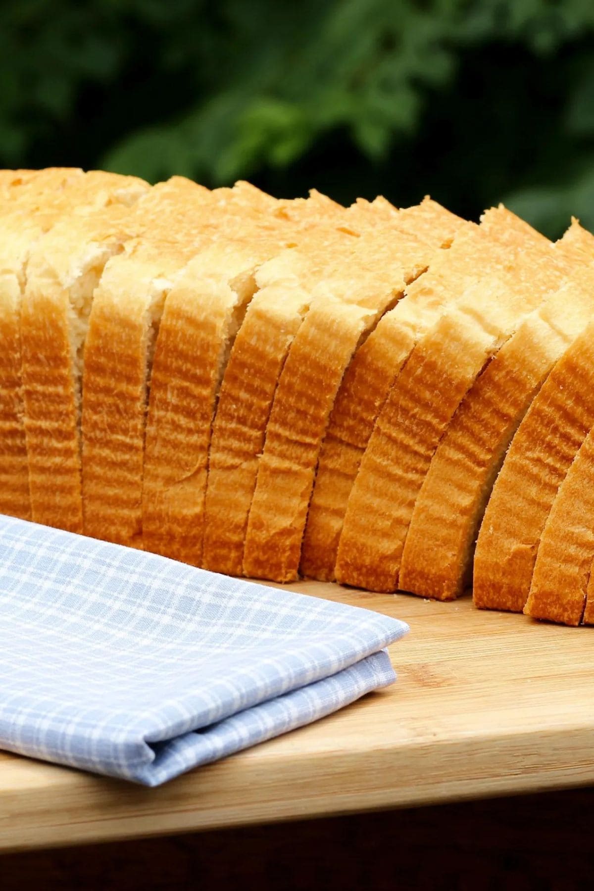 Large loaf of bread sliced into slices with a folded blue linen napkin.