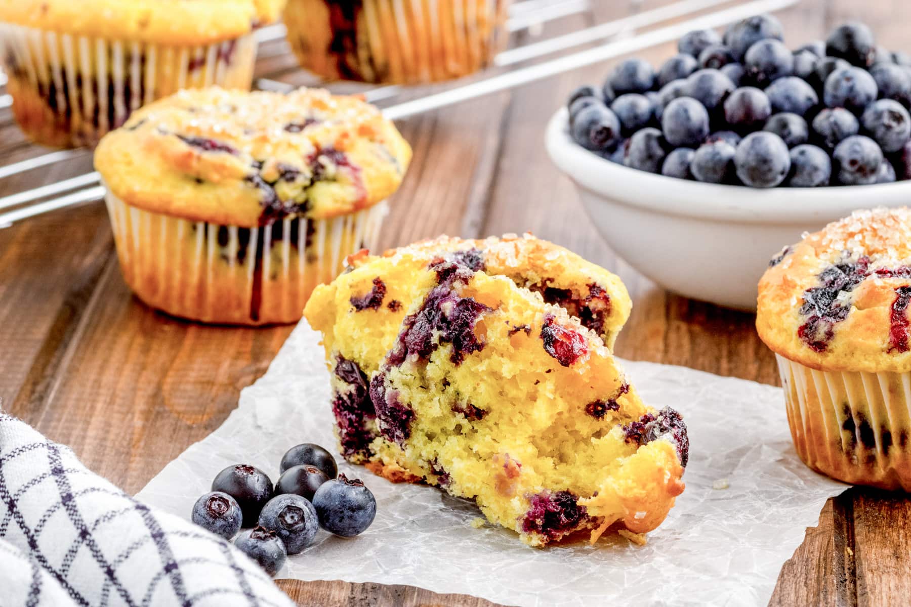 Serving warm lemon-blueberry muffins, sliced in half, on a slice of parchment paper.