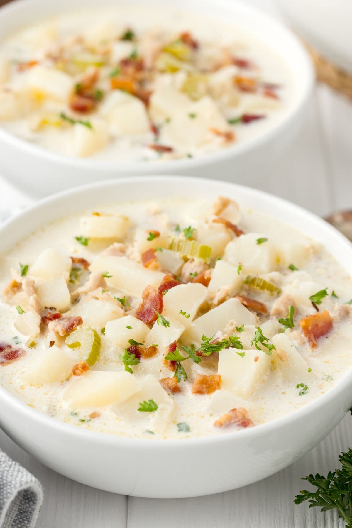 2 bowls of clam chowder are served on a table.