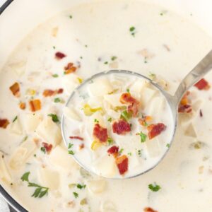 New England Clam Chowder in a large pot with a soup ladle.