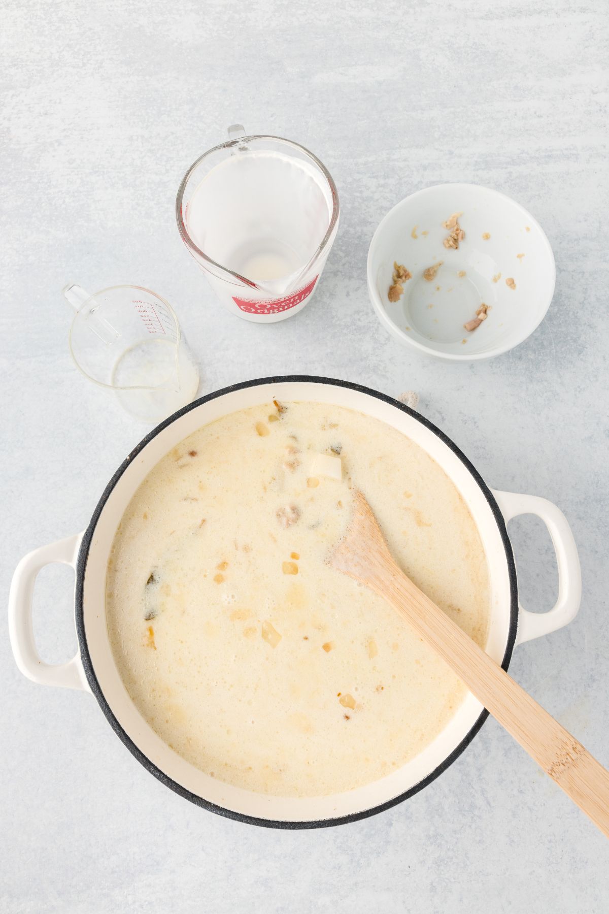 clam chowder in a large pot with a wooden spoon