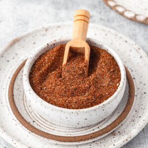 A small bowl holding a spice mix of chicken taco seasoning with a small wooden spoon digging in it.