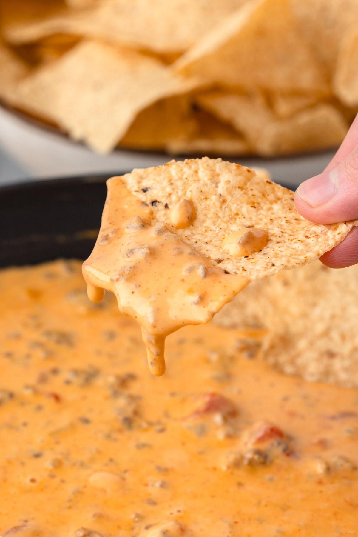 up close photo of a creamy cheese drip on a tortilla chip