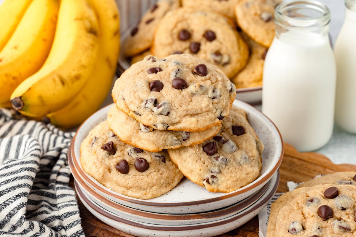 Buttery chocolate chip cookies with bananas and milk in the background, fresh baked goods ready to enjoy.