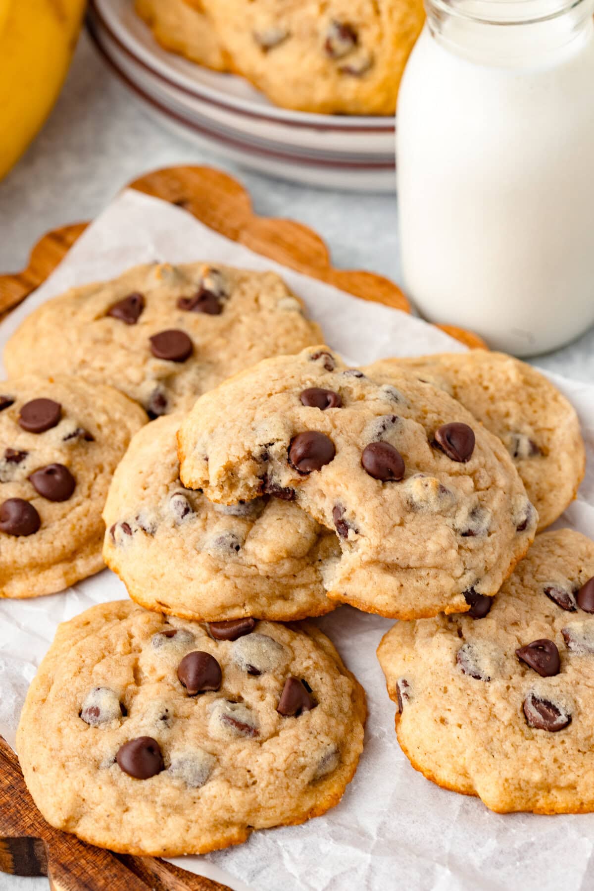 Butter cookies with chocolate chips on a wooden tray, with a jar of milk in the background, styled for a cozy snack.