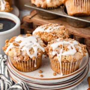 Three Coffee Cake Muffins on stacked plates with a cup of coffee beside.
