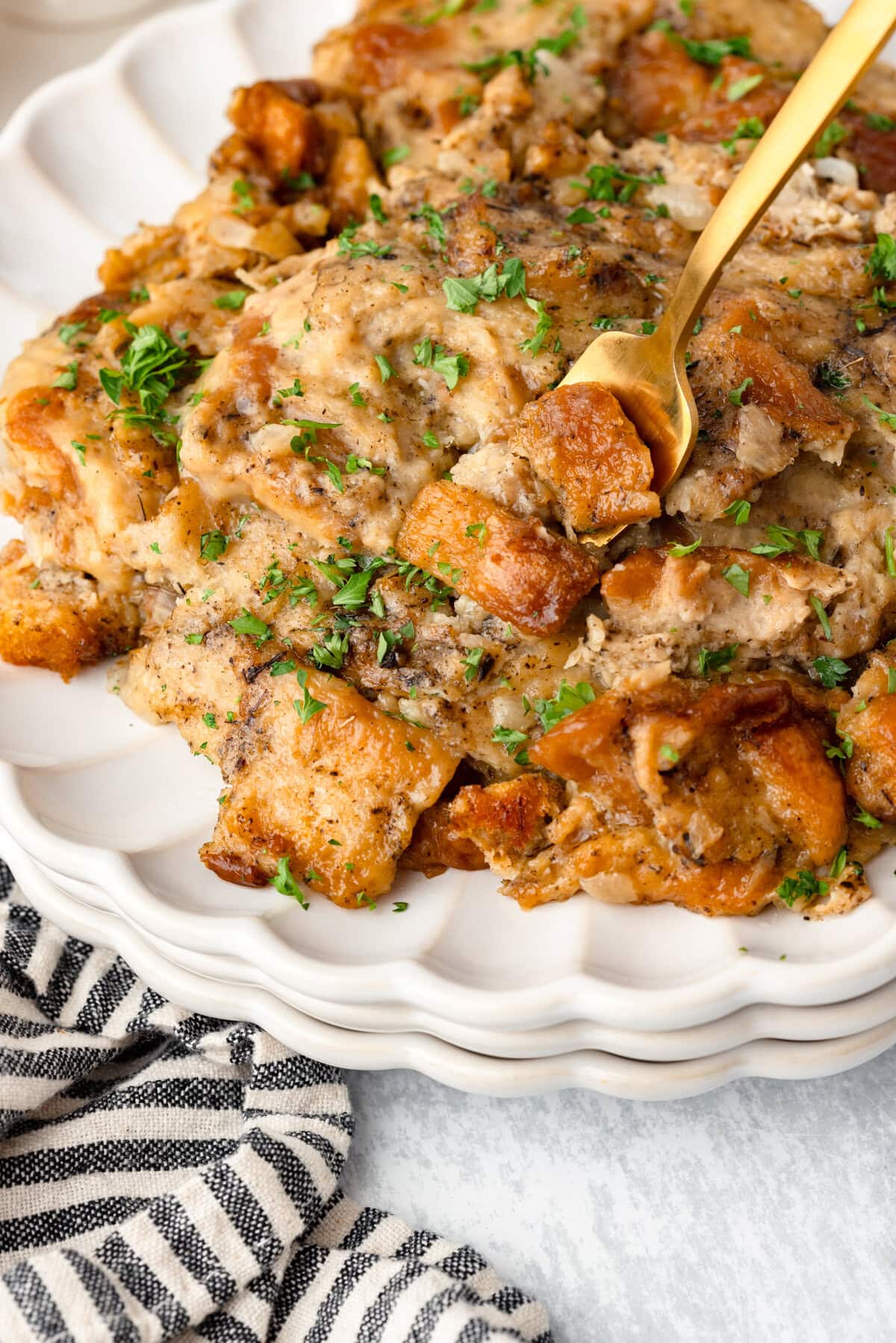 Creamy baked chicken and vegetable casserole garnished with fresh parsley on a decorative white plate.