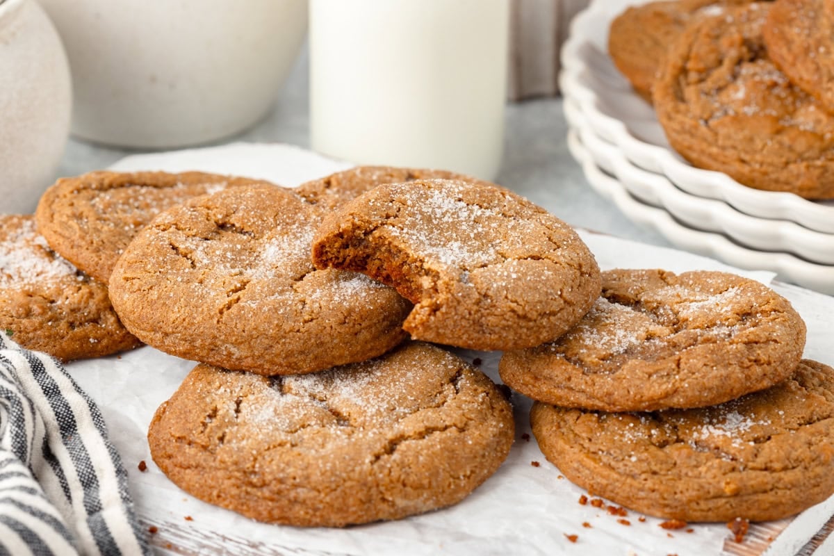 Soft, freshly baked chocolate chip cookies dusted with powdered sugar on a rustic surface.