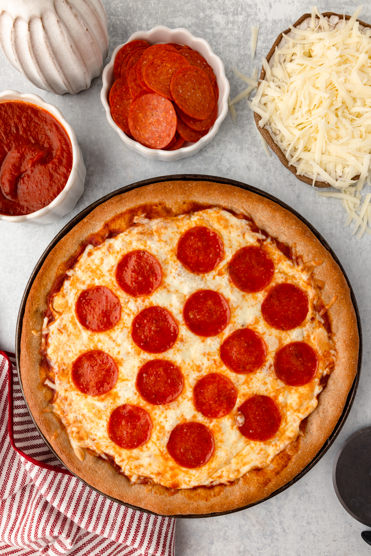 Cheese and pepperoni pizza with side toppings of tomato sauce, sliced pepperoni, shredded cheese, and pizza crust.
