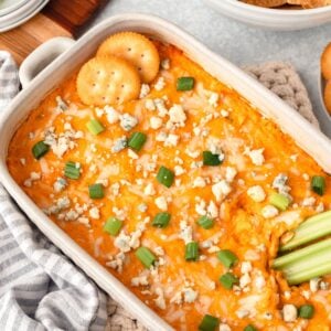 Buffalo Style Chicken Dip garnished with green onions, blue cheese crumbles, and crackers.