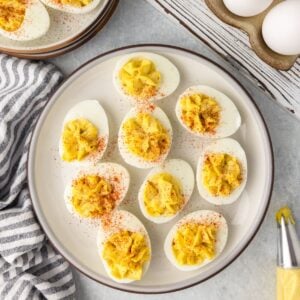 A plate of deviled eggs recipe with smooth, creamy centers and a dusting of paprika.