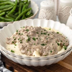 Hamburger Gravy served over mashed potatoes with green beans in the back.