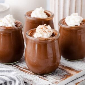 Creamy homemade chocolate pudding in glass jars with whipped cream topping.