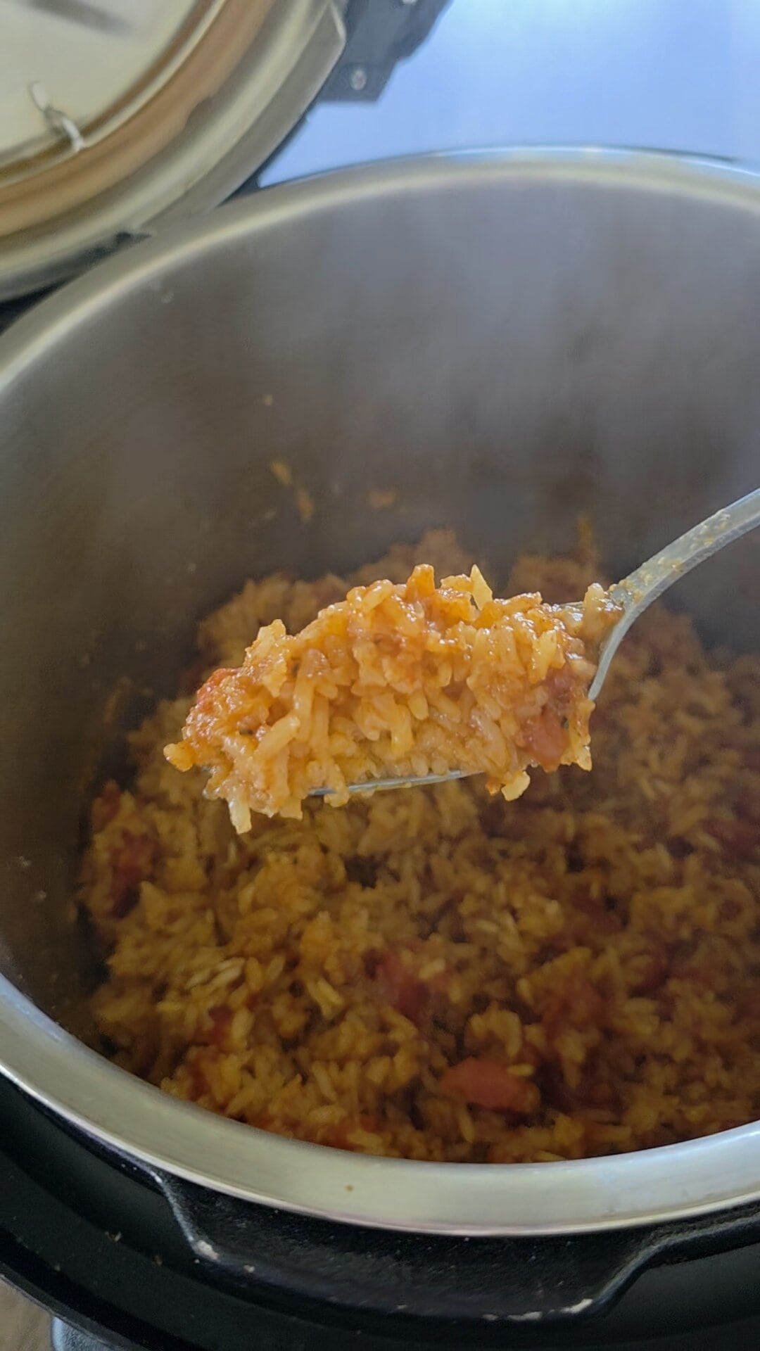 Fluffy Mexican Rice in a rice cooker with a spoonful being lifted out.