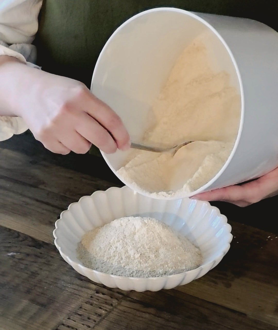 Freshly milled whole wheat flour being scooped into a bowl.