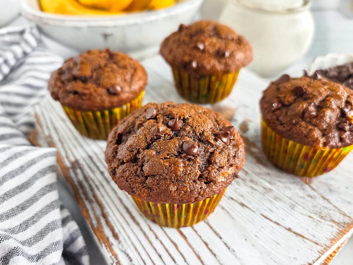 Delicious chocolate chip muffins on a rustic wooden surface.