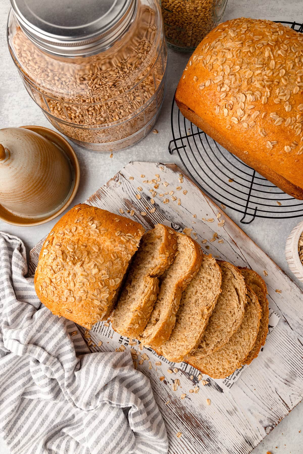 Fresh homemade oat bread sliced on a rustic wooden surface with baking ingredients nearby.