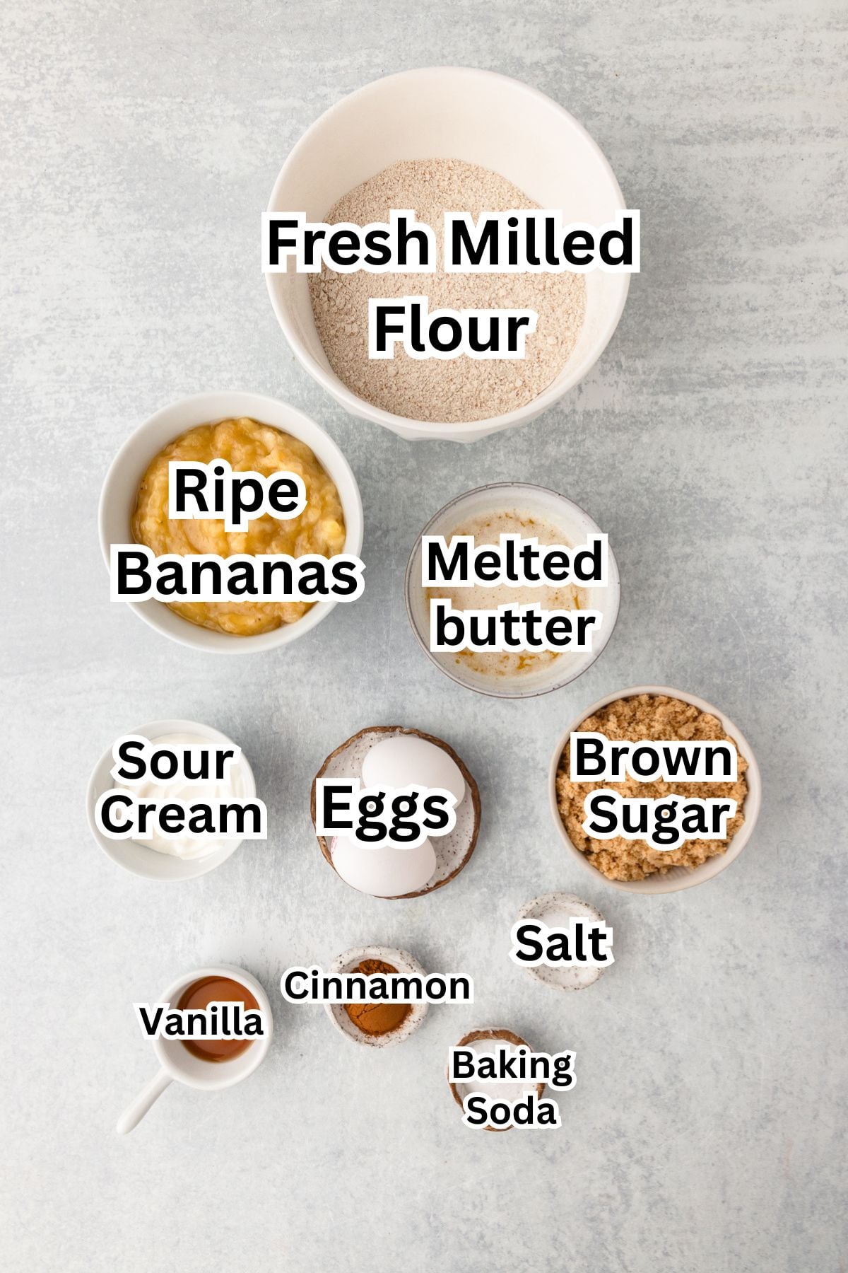 Banana bread ingredients with fresh milled flour and ripe bananas on a gray surface.