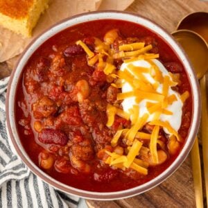 Overhead shot of slow cooker beef chili in a bowl with cheese and sour cream.