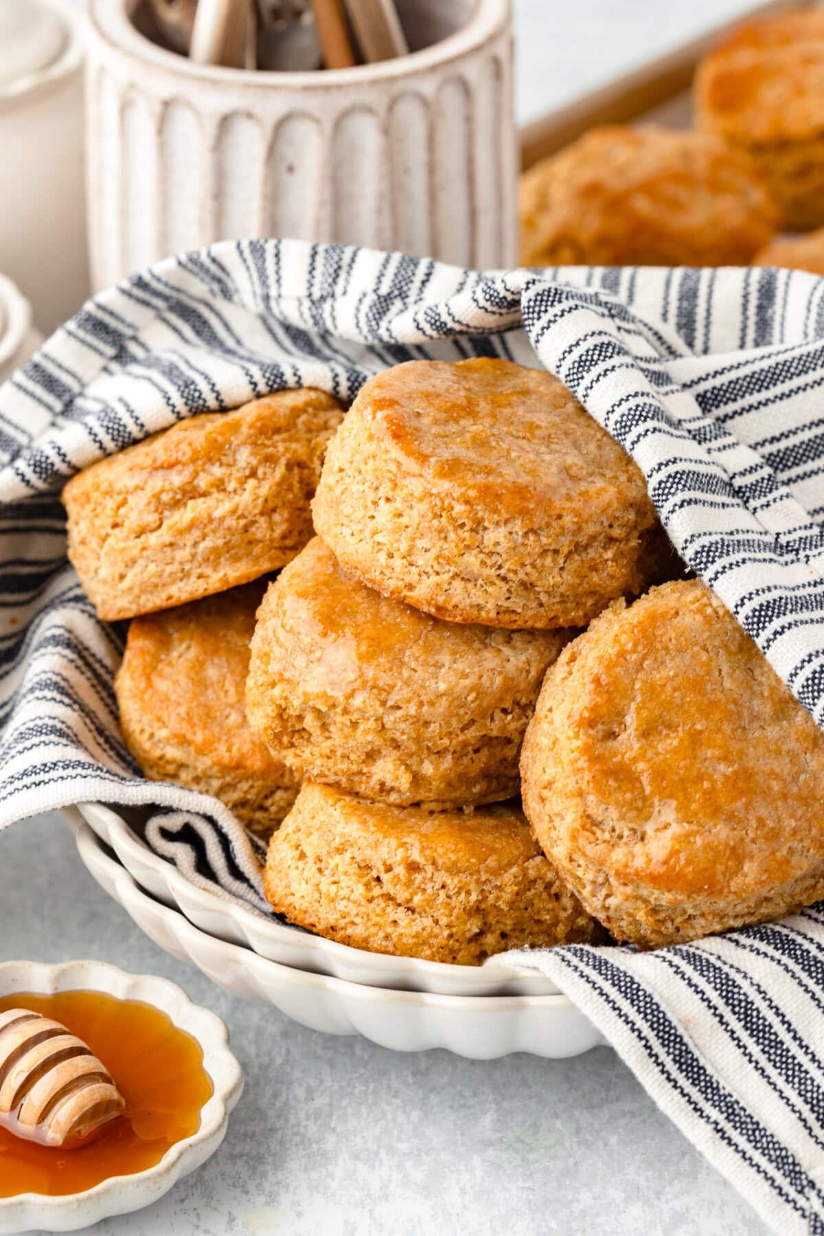 Whole wheat biscuits with a golden, crispy exterior in a basket with a striped cloth.